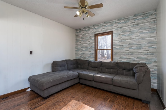 living room with ceiling fan, dark hardwood / wood-style flooring, and a textured ceiling