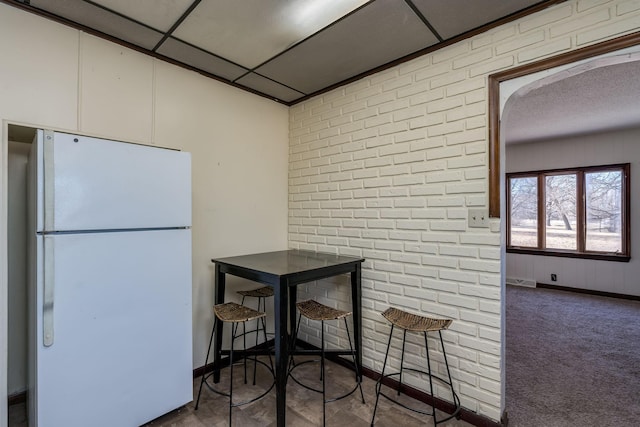 kitchen featuring carpet floors, a paneled ceiling, brick wall, and white refrigerator