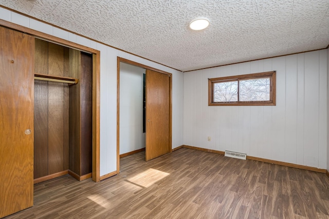 unfurnished bedroom with dark hardwood / wood-style flooring and crown molding