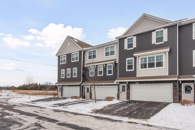 view of property with driveway, stone siding, and an attached garage