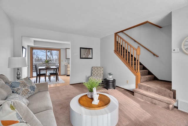 carpeted living room featuring stairs, a textured ceiling, visible vents, and baseboards