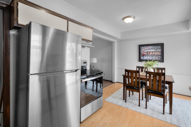 kitchen with white cabinets, stainless steel appliances, light wood-style flooring, and under cabinet range hood