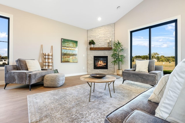 living room featuring hardwood / wood-style flooring, a stone fireplace, and high vaulted ceiling