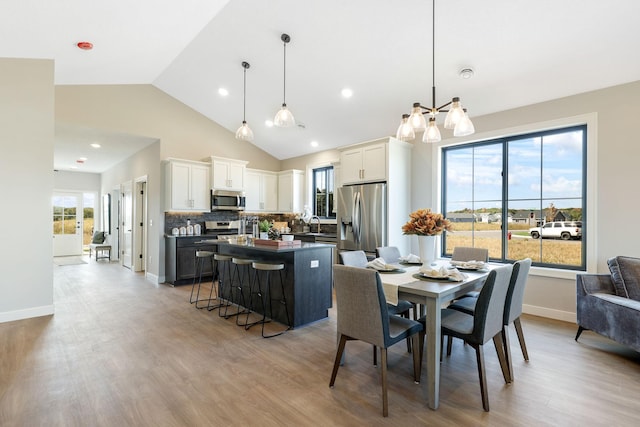 dining space featuring high vaulted ceiling, sink, and light hardwood / wood-style floors