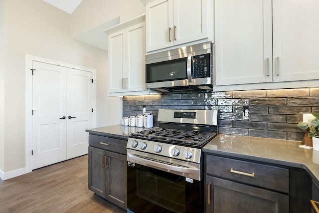 kitchen featuring appliances with stainless steel finishes, wood-type flooring, white cabinets, backsplash, and dark brown cabinetry