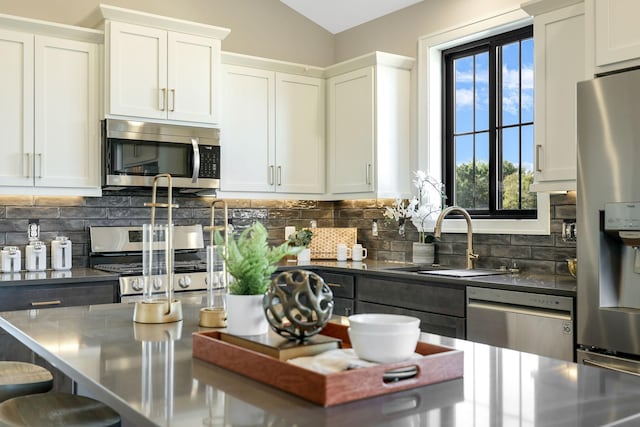 kitchen featuring sink, backsplash, stainless steel appliances, and white cabinets