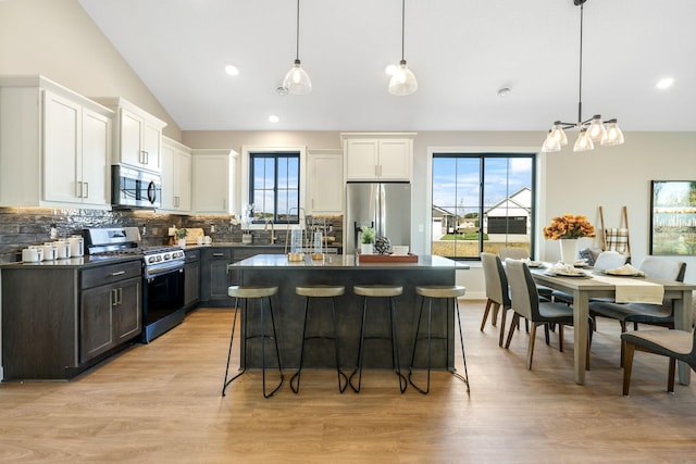 kitchen featuring decorative light fixtures, stainless steel appliances, white cabinets, and a kitchen island