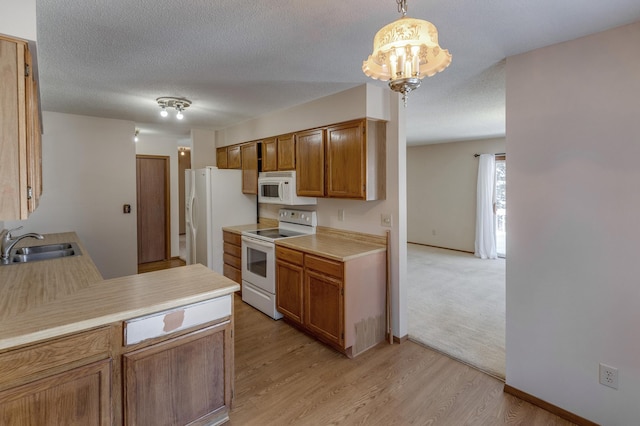 kitchen with hanging light fixtures, white appliances, light wood-type flooring, a textured ceiling, and sink