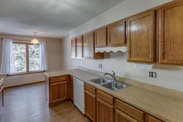 kitchen featuring kitchen peninsula, hanging light fixtures, light hardwood / wood-style flooring, sink, and dishwasher