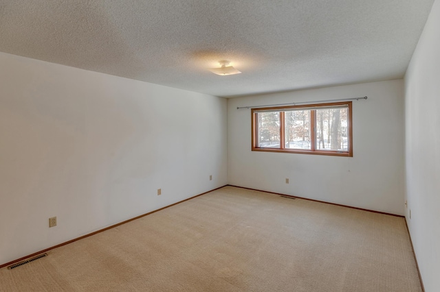 empty room featuring a textured ceiling and light carpet