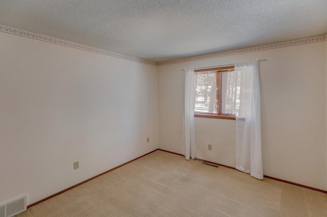 unfurnished room with a textured ceiling and light colored carpet