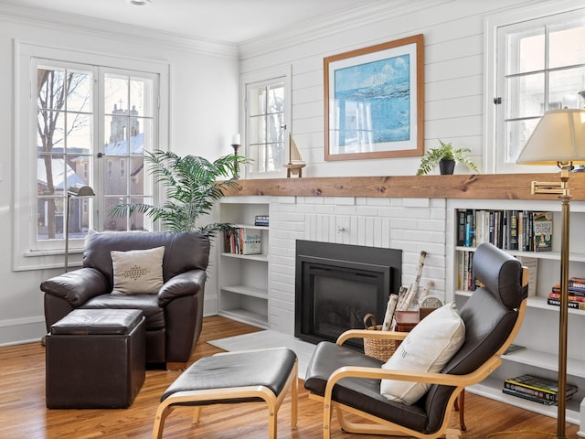 living area featuring a fireplace, crown molding, a wealth of natural light, and light hardwood / wood-style floors