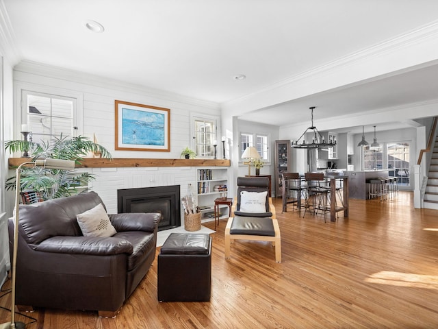 living room featuring an inviting chandelier, ornamental molding, hardwood / wood-style floors, and a fireplace