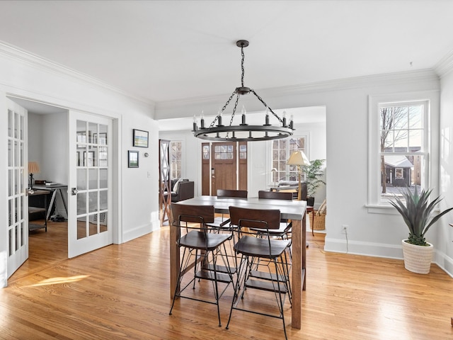 dining area featuring ornamental molding, french doors, and light wood-type flooring