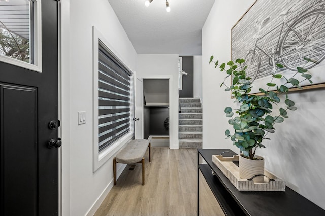 corridor with light hardwood / wood-style flooring and a textured ceiling