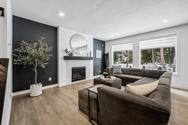 living room with plenty of natural light, a textured ceiling, a fireplace, and light hardwood / wood-style floors