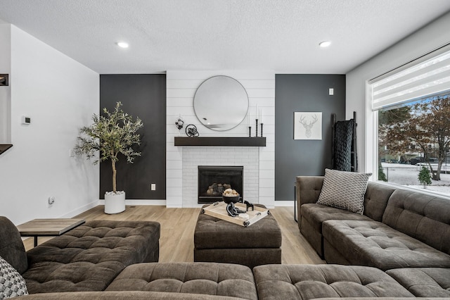 living room with a large fireplace, light hardwood / wood-style flooring, and a textured ceiling