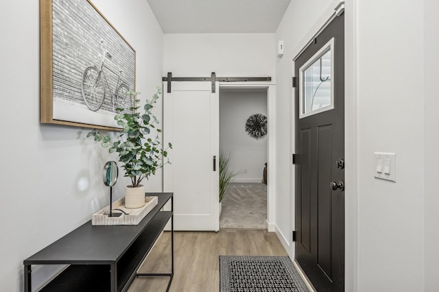 doorway to outside featuring a barn door and light hardwood / wood-style floors