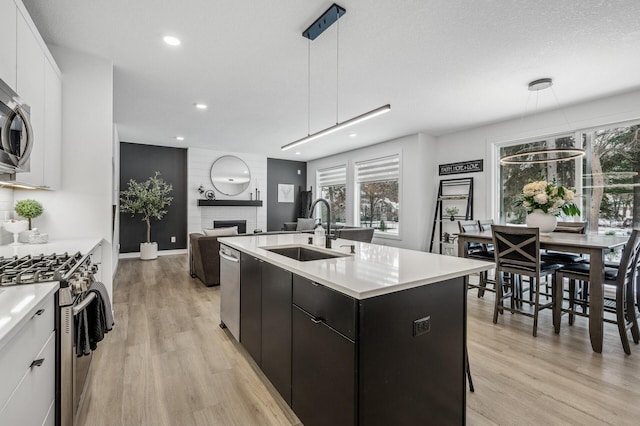 kitchen featuring appliances with stainless steel finishes, sink, white cabinets, and decorative light fixtures