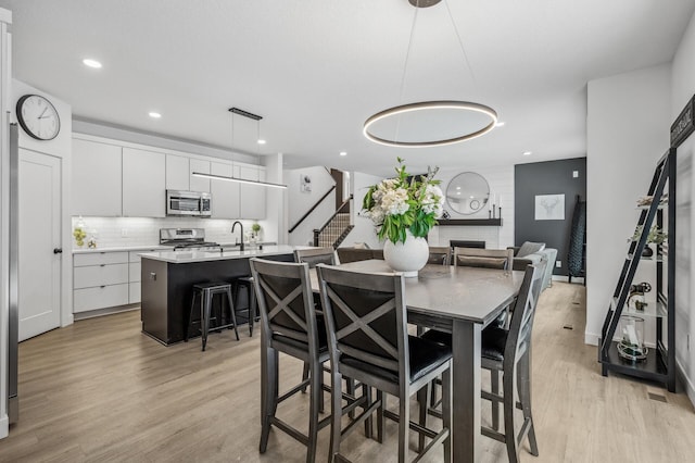 dining room featuring a large fireplace, sink, and light hardwood / wood-style floors