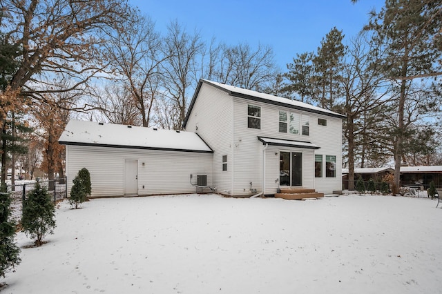 snow covered back of property featuring central air condition unit