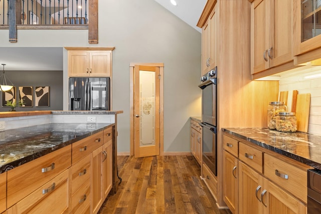 kitchen featuring high vaulted ceiling, dark hardwood / wood-style floors, decorative light fixtures, black refrigerator with ice dispenser, and stainless steel double oven