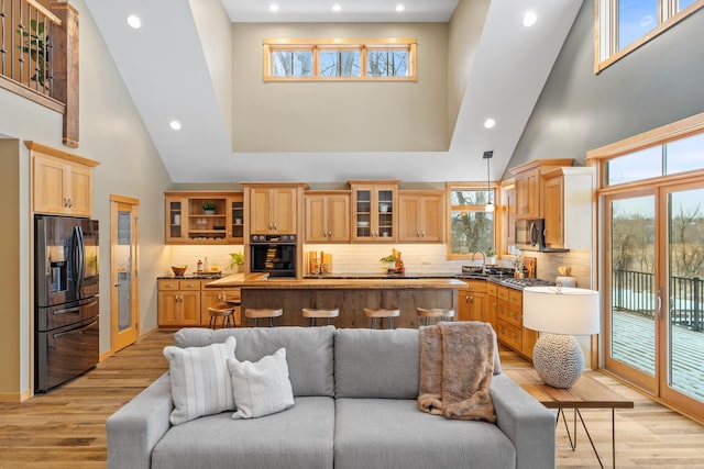 living room featuring a high ceiling, sink, and light hardwood / wood-style floors