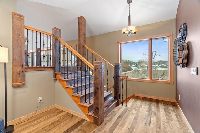 stairs featuring wood-type flooring and a chandelier