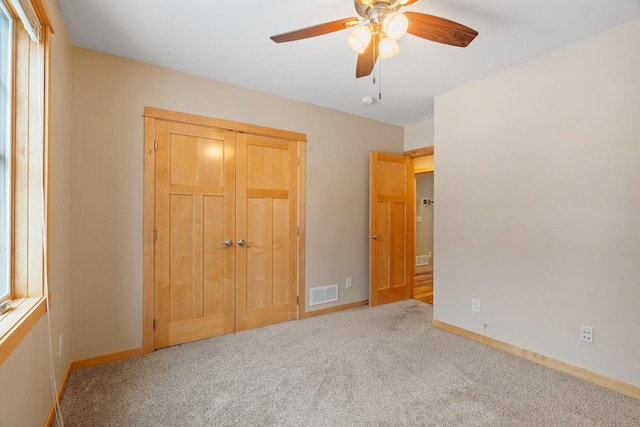 unfurnished bedroom featuring light carpet, ceiling fan, and a closet