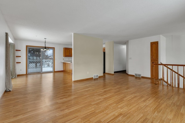 unfurnished living room featuring a chandelier and light hardwood / wood-style floors