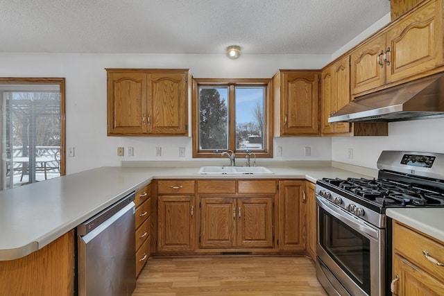 kitchen with appliances with stainless steel finishes, sink, a textured ceiling, and kitchen peninsula