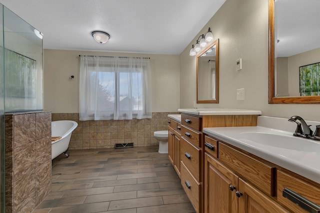 bathroom with vanity, toilet, tile walls, and a tub