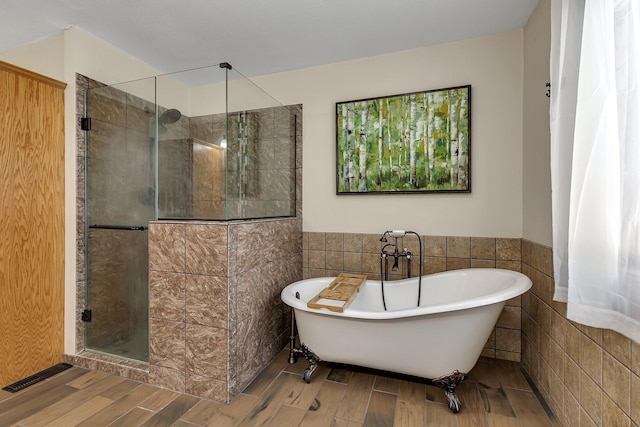 bathroom featuring tile walls, wood-type flooring, and shower with separate bathtub