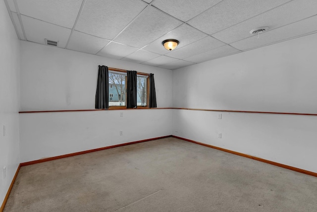 carpeted empty room with a paneled ceiling