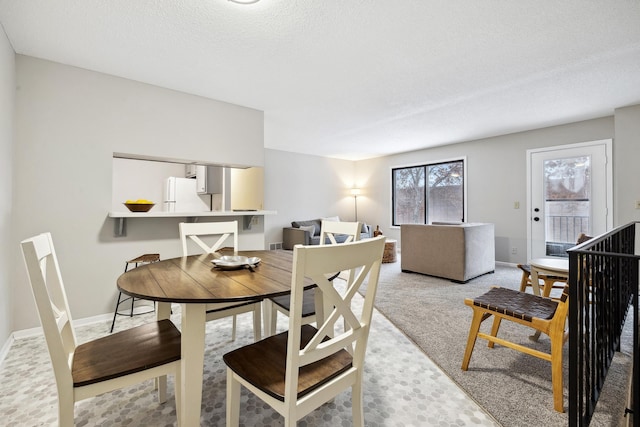 carpeted dining area featuring a textured ceiling