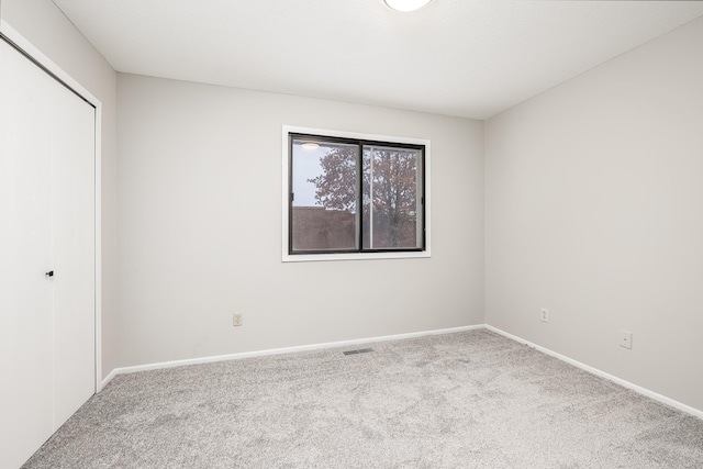 unfurnished bedroom featuring light colored carpet and a closet