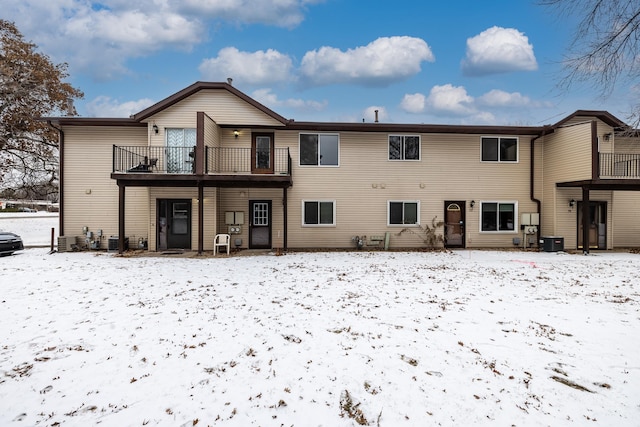 snow covered back of property with a balcony and central air condition unit