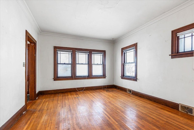 empty room featuring a wealth of natural light, ornamental molding, and wood-type flooring