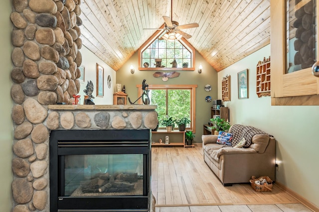 living room featuring ceiling fan, a fireplace, light hardwood / wood-style floors, vaulted ceiling, and wooden ceiling