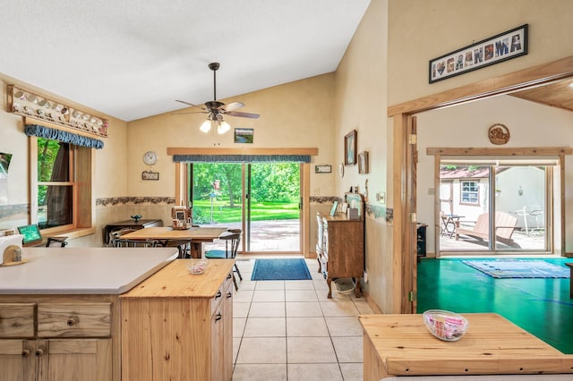 kitchen featuring lofted ceiling, butcher block counters, light tile patterned floors, ceiling fan, and light brown cabinets