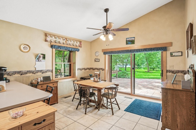 tiled dining space with ceiling fan, a healthy amount of sunlight, and vaulted ceiling