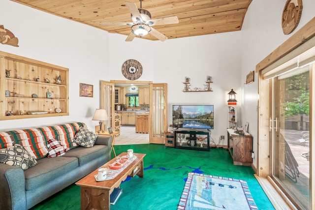 carpeted living room with ceiling fan, a towering ceiling, and wood ceiling