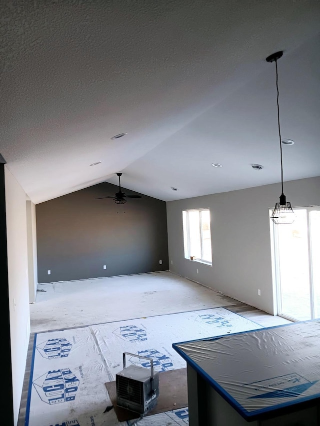 empty room with vaulted ceiling, a textured ceiling, and ceiling fan