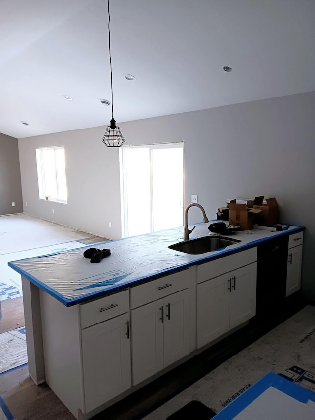 kitchen with white cabinetry, sink, decorative light fixtures, and an island with sink