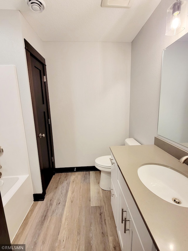 bathroom with vanity, hardwood / wood-style flooring, a textured ceiling, and toilet