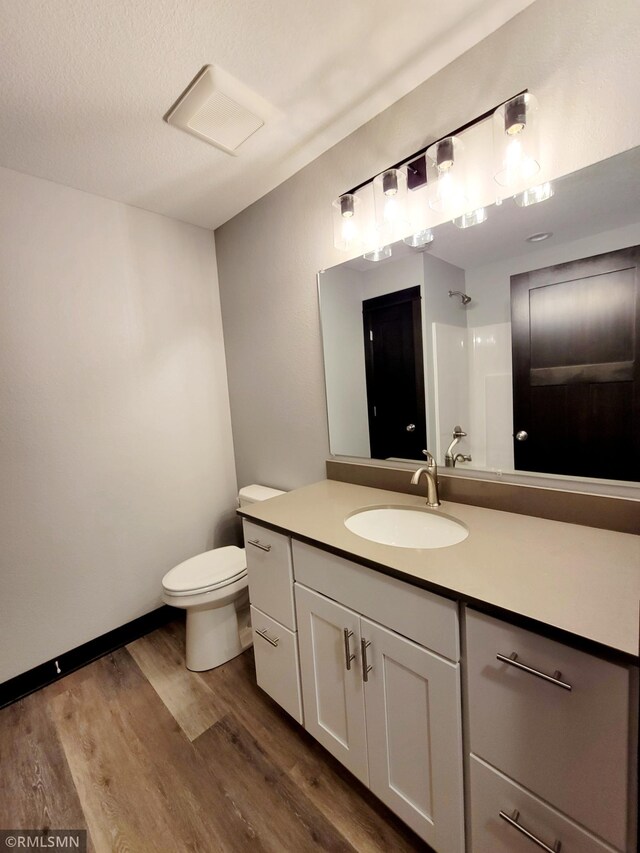 bathroom featuring hardwood / wood-style floors, vanity, a textured ceiling, a shower, and toilet