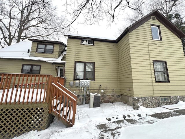 snow covered property featuring a wooden deck and central AC