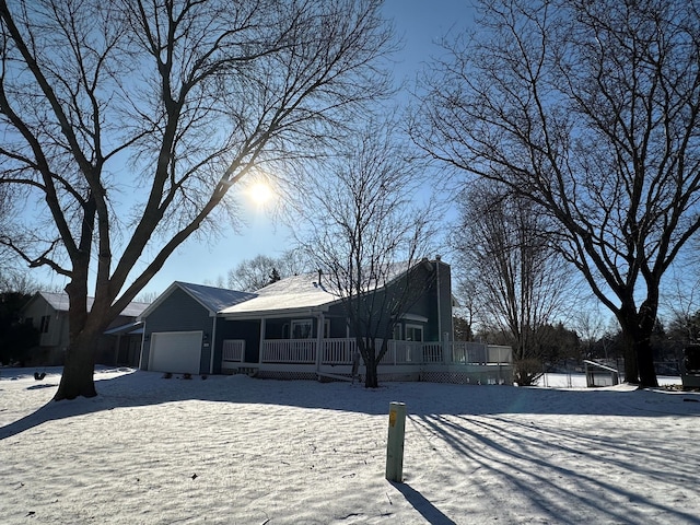 snow covered house featuring a garage and covered porch