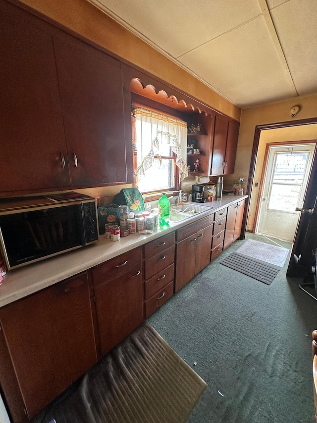 kitchen with a sink, open shelves, carpet floors, black microwave, and light countertops