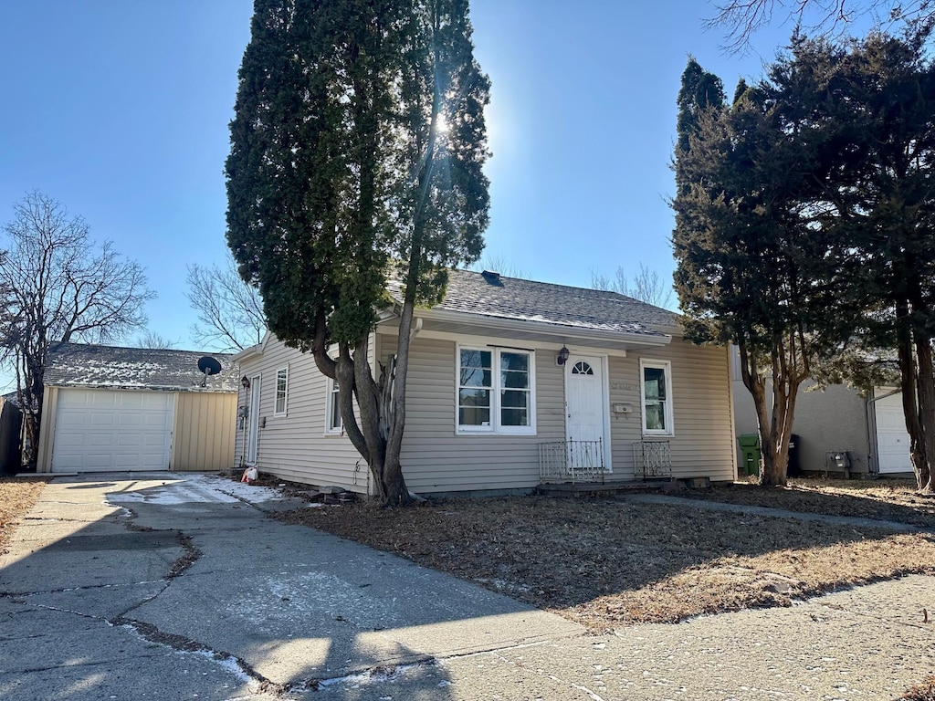 ranch-style home with a garage, concrete driveway, and a shingled roof
